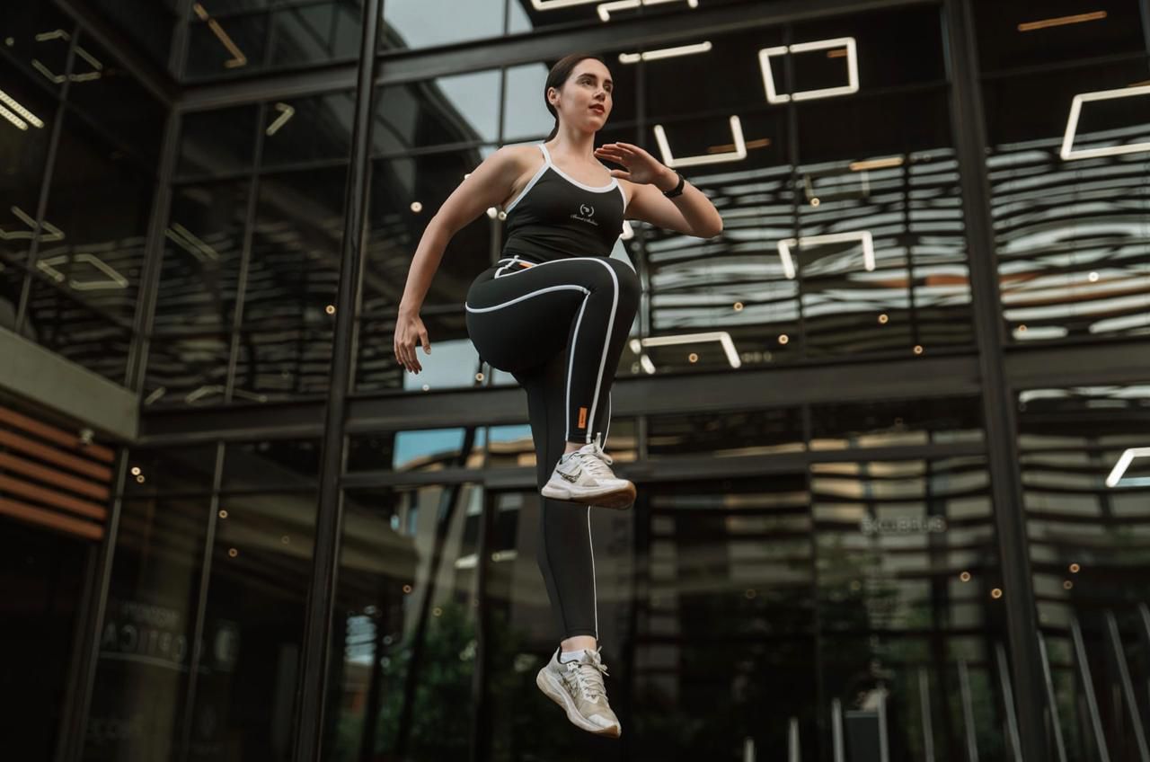Jani demonstrating a dynamic knee-lift exercise in a gym