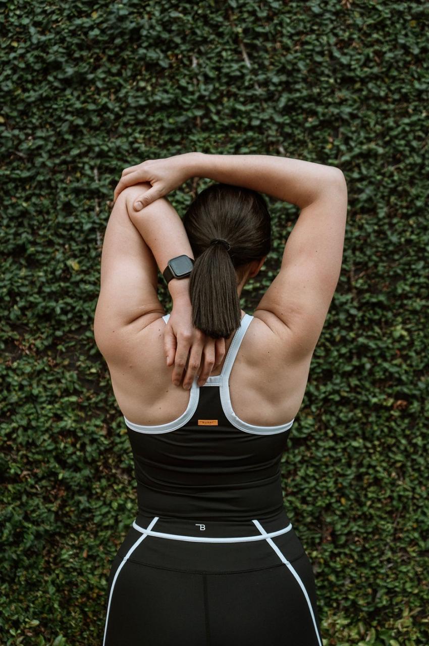 Jani stretching outdoors, photographed from behind